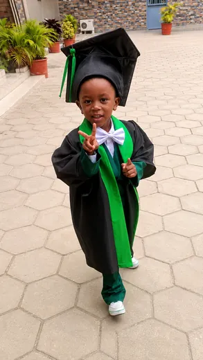 Un petit diplômé en toge et toque, le sourire aux lèvres