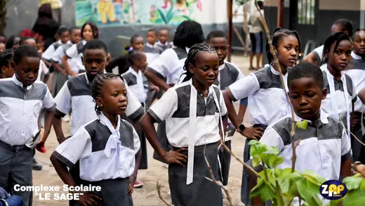 Les élèves en uniforme gris et blanc, rassemblés dans la cour